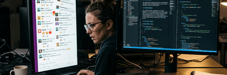 Developer working at computer with chat window about API down and coding screens